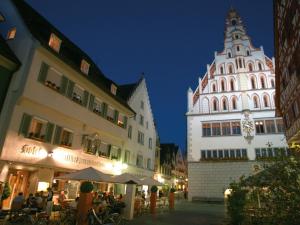 una strada con due edifici e una torre dell'orologio di notte di Hotel Restaurant Grüner Baum und Altes Tor a Bad Waldsee