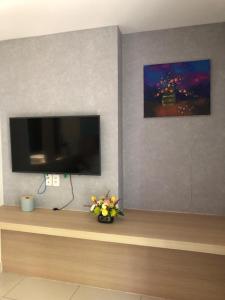 een woonkamer met een tv en bloemen op een tafel bij Oceanami Villas & Beach Club 3 bedroom villa in Long Hai