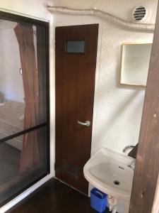 a bathroom with a toilet and a sink and a door at ゲストハウス303 in Zamami