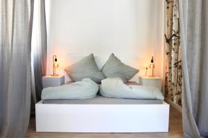 Sofá blanco con almohadas y 2 lámparas en Vier Sind Hier Apartments en Rottweil