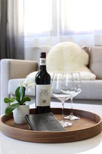 a bottle of wine on a wooden tray with wine glasses at Vier Sind Hier Apartments in Rottweil