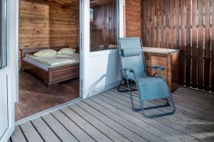 una silla azul sentada en un porche con cama en Nameliai ant ežero kranto, en Kaišiadorys