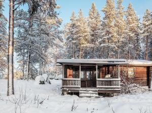 una cabaña en el bosque con nieve en el suelo en Blockhaus am See en Arvidsjaur