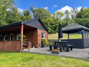 a cabin with a picnic table and an umbrella at Kabin in the woods in Llandybie