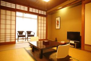 - un salon avec une télévision, une table et des chaises dans l'établissement 城崎温泉 旅館 つばき乃 - Kinosaki Onsen Ryokan Tsubakino, à Toyooka