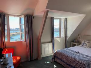 a bedroom with a bed and two windows at Hotel du Centre - Chez Janie in Roscoff