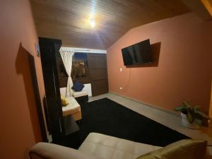 a living room with a couch and a tv on the wall at Hospedaje Aquitoy Sanoha in Monguí
