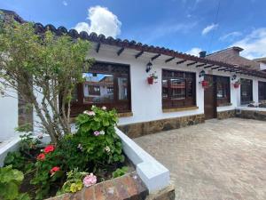 a house with a courtyard with flowers in front of it at Hospedaje Aquitoy Sanoha in Monguí