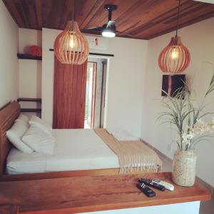 a bedroom with a bed with two lamps and a table at Hakuna Studios Barra do Sahy in Barra do Sahy