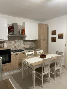 una cucina con tavolo e sedie e una cucina con armadietti bianchi di Casa vacanza al N.56 A POLLINA a Pollina