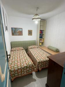 una piccola camera con due letti e un divano di Casa vacanza al N.56 A POLLINA a Pollina