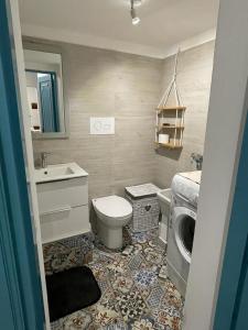 a bathroom with a toilet and a sink and a washing machine at Casa vacanza al N.56 A POLLINA in Pollina