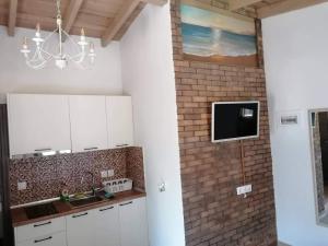 uma cozinha com armários brancos e uma televisão numa parede de tijolos em Tiny house by the sea em Nea Skioni