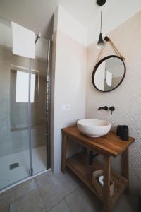 uma casa de banho com um lavatório, um chuveiro e um espelho. em Dimorae Camà em Cisternino