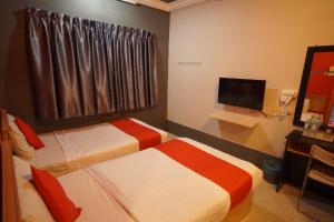 Cette chambre comprend deux lits et une télévision. dans l'établissement V HOTEL, à Teluk Intan
