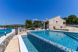 a swimming pool with blue water and a stone building at Villa Rudini with heated pool in Okrug Gornji