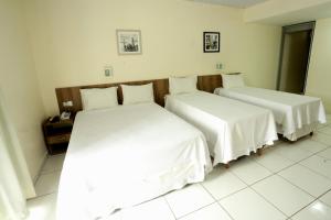 two beds in a hotel room with white sheets at Boulevard Park Hotel in São Luís