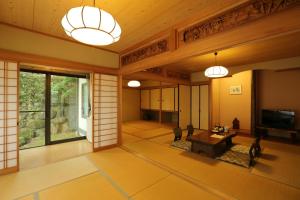 a living room with a table and a tv at Tawarayama Onsen Ryokan Minawa in Minami Aso