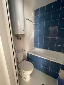 een blauwe betegelde badkamer met een toilet en een bad bij Villa Flora SP apartments in Ravda