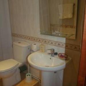 ein Badezimmer mit einem Waschbecken, einem WC und einem Spiegel in der Unterkunft Pension Gades in Cabezón de la Sal