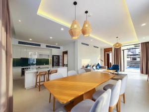 cocina y comedor con mesa de madera y sillas en Luxury villa trong Whyndham garden Cam Ranh en Nha Trang