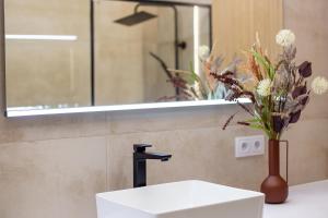 a bathroom sink with a mirror and a vase with flowers at Hillside7 Micro-Apartment 16 in Bielsko-Biała