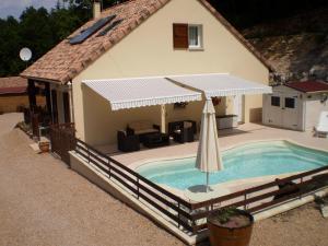 a house with a swimming pool with an umbrella at Les Roziers - Roulotte in Bagnac