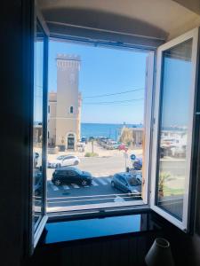 a window with a view of a parking lot and a lighthouse at Mydollhouse delizioso appartamento fronte mare in Genoa