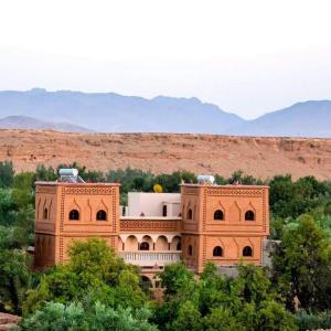 a large brick building in the middle of trees at kasbah amlal in Tinerhir