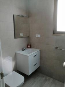 een badkamer met een toilet, een wastafel en een spiegel bij 3Arguineguin terrasse apart next to beach in Arguineguín