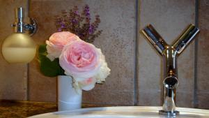 a vase of pink roses sitting on a bathroom sink at JANISCHs Fewo im Spreewald in Neu Lübbenau