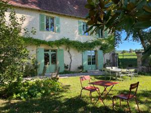 a house with chairs and a table in the yard at Le Clos Chalmon Chambre d'hôte in Montignac