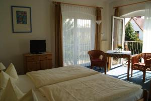 a bedroom with a bed and a table and a balcony at Pension Waldeck in Göhren