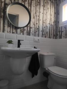 a bathroom with a sink and a toilet and a mirror at Apartamento espacioso, nuevo, luminoso y acogedor in Casar de Cáceres