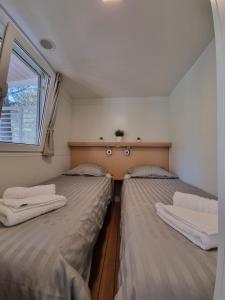 Premium Mobile Home ZEN SPOT 277 في يزيرا: سريرين في غرفة صغيرة مع نافذة