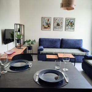 a living room with a table and a blue couch at Apartament Burgund Wyspa Sobieszewska in Gdańsk