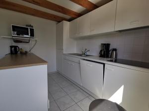 a kitchen with white cabinets and a microwave at Griad in de Duinen in De Haan +9 photos