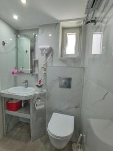 a white bathroom with a toilet and a sink at Alfa Studio in Kavála