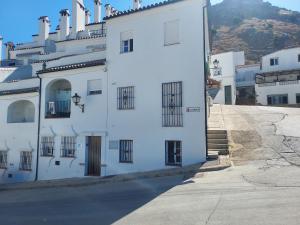 a white building with black barred windows on a street at Con el Alma in Benaocaz