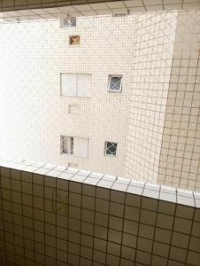 a bathroom with white tiled walls and windows at Apartamento Vidal con Wi-Fi Praia Grande Avi in Praia Grande