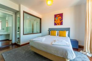 um quarto com uma cama com almofadas amarelas e um espelho em FLH Funchal Artistic Apartment with Balcony em Funchal
