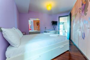 a bedroom with a white bed with a purple wall at FLH Funchal Artistic Apartment with Balcony in Funchal