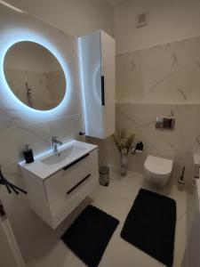 a bathroom with a sink and a toilet and a mirror at KARINA APARTMAN in Dunajská Streda