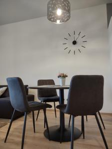 a table with four chairs and a clock on the wall at KARINA APARTMAN in Dunajská Streda