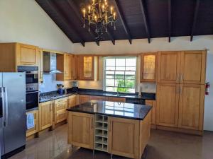 a large kitchen with wooden cabinets and a chandelier at Breezy Ocean Front Condo Close to The Best Beaches in Christ Church