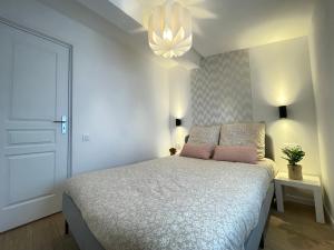 a bedroom with a white bed with a pink pillow at Nice Renting - FERSEN - 2 Rooms Vieil Antibes - AC - Safranier - Big Terrace in Antibes