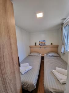 two beds in a small room with a window at Premium Mobile Home ZEN SPOT 279 in Jezera