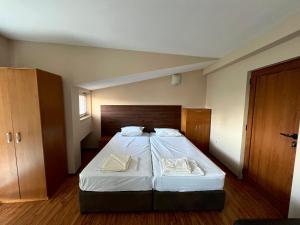 een slaapkamer met een groot bed met witte lakens bij Hotel Maria in Vratsa