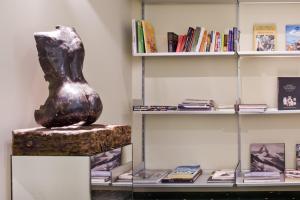 a vase on a stand in front of a book shelf at Hotel Zaragoza Plaza in Donostia-San Sebastián