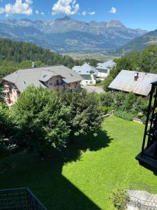 ein grüner Hof mit einem Haus und Bergen im Hintergrund in der Unterkunft Mont Blanc Residence in Saint-Gervais-les-Bains